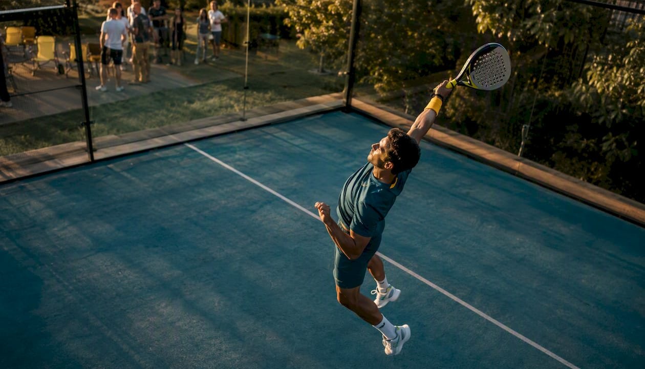 Male player swinging padel racket outdoors