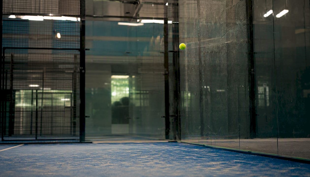 Padel ball bouncing off glass wall