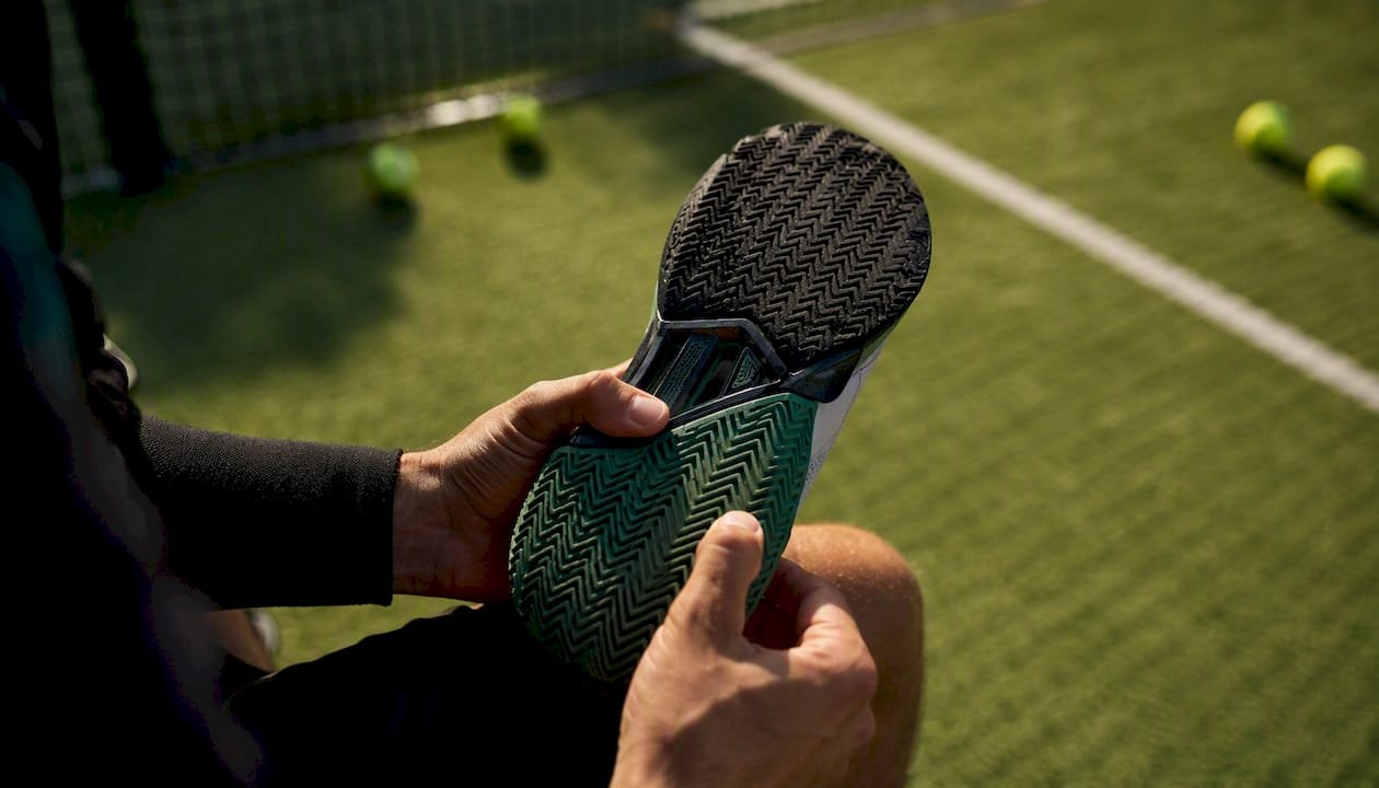 Hands inspecting padel shoe sole tread depth