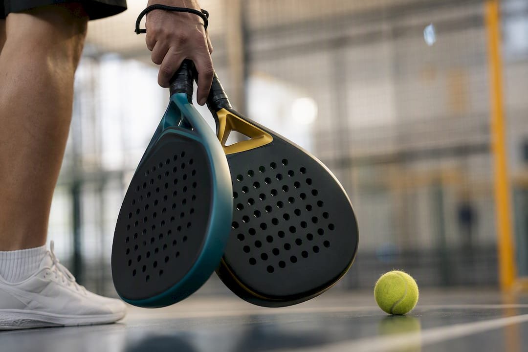 Hands holding two different padel racket shapes