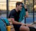 Padel player using towel on outdoor court bench
