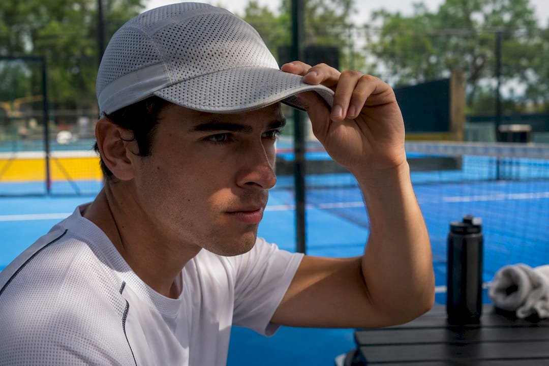 Padel player adjusting sun protection cap