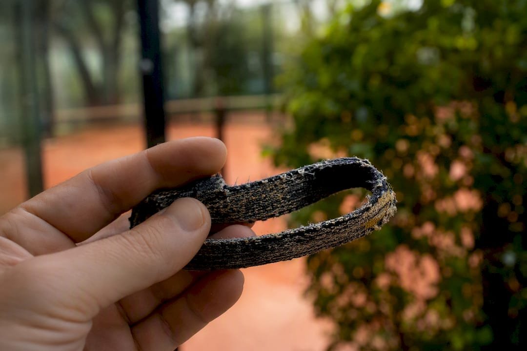 Worn padel wrist strap with fraying and cracks