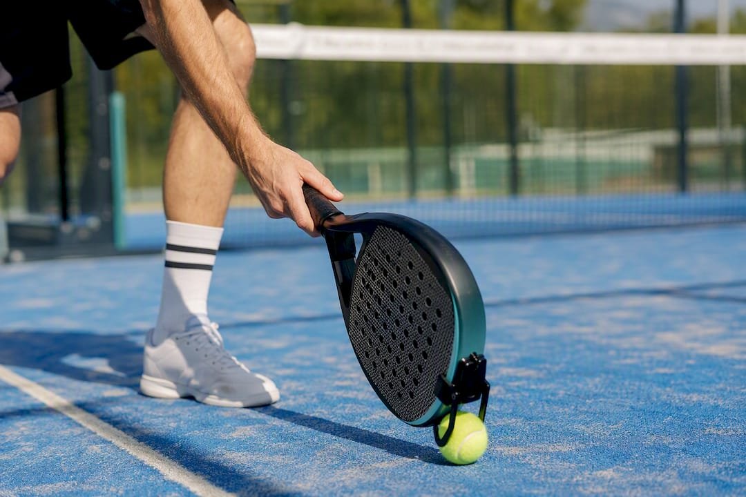 Player using racket-mounted padel ball picker