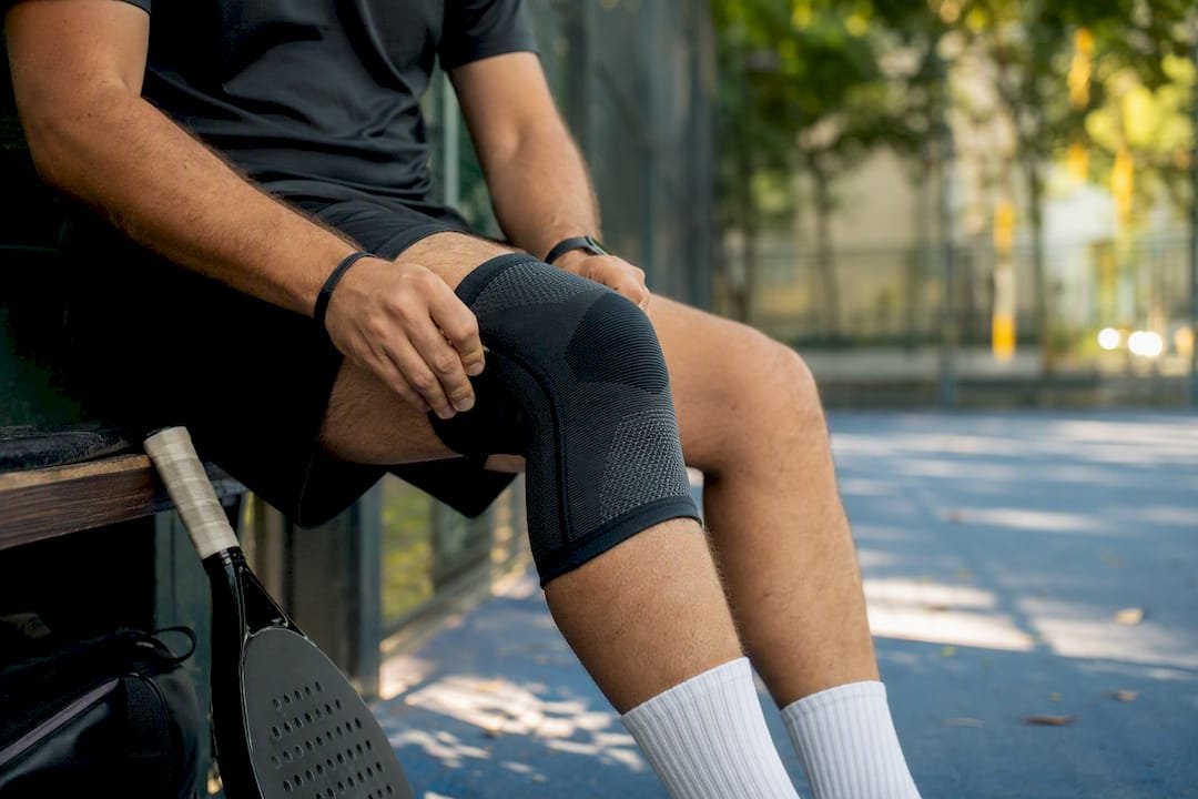 Padel player adjusting knee compression sleeve