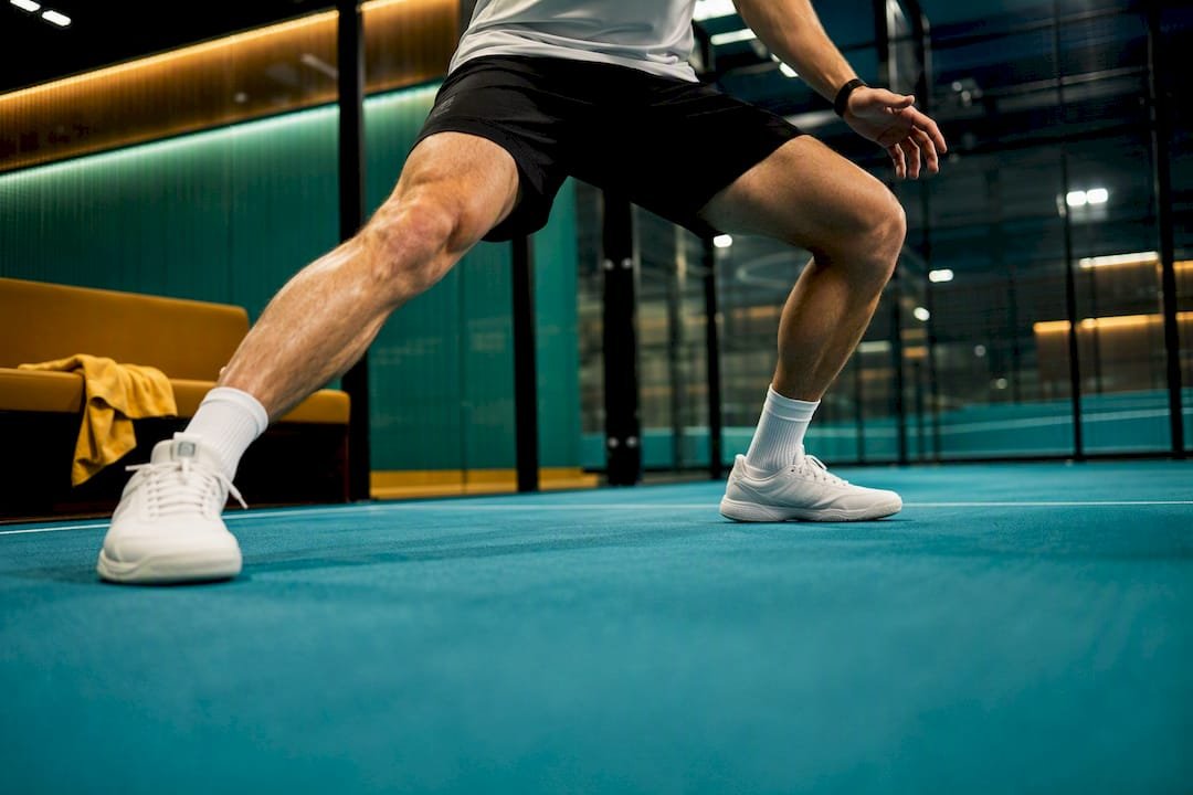 Player making lateral split-step on padel court